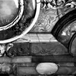 Czarno biała fotografia przedstawia fragment korpusu szkatuły. Widoczne zdobienia roślinne i połączenia płytek bursztynowych.